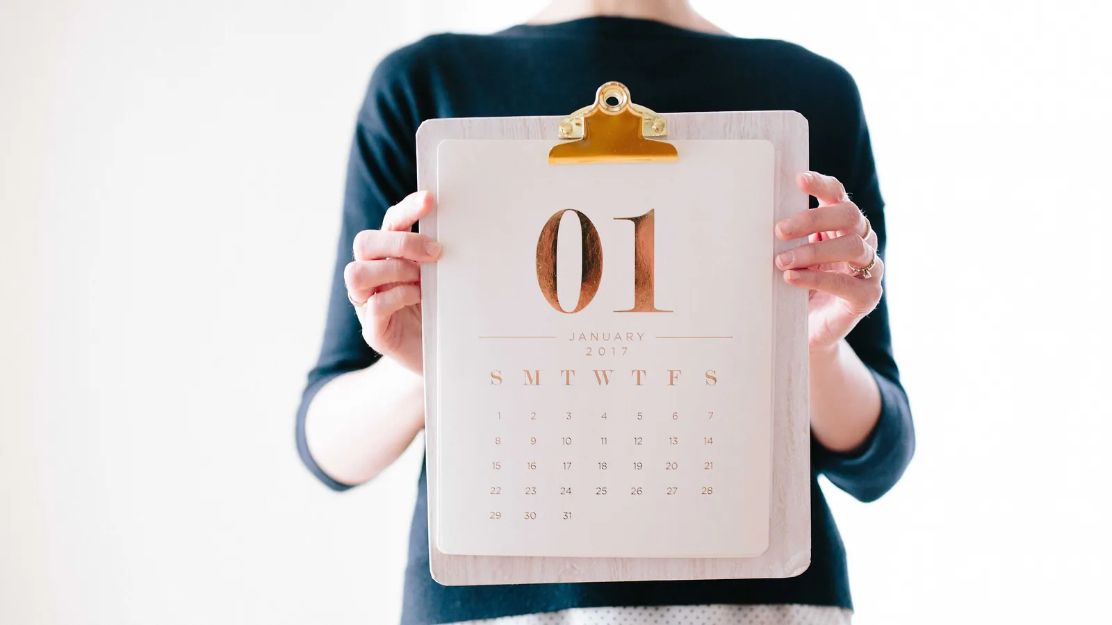 A person holding a clipboard calendar turned to January 1